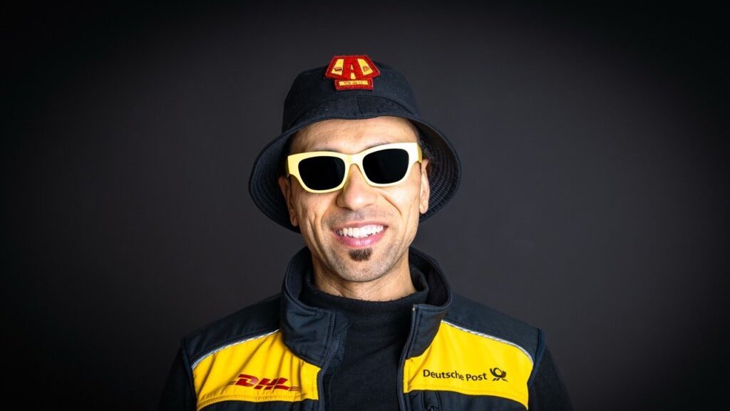 Lachender Postbote in Uniform mit Hut und Sonnenbrille