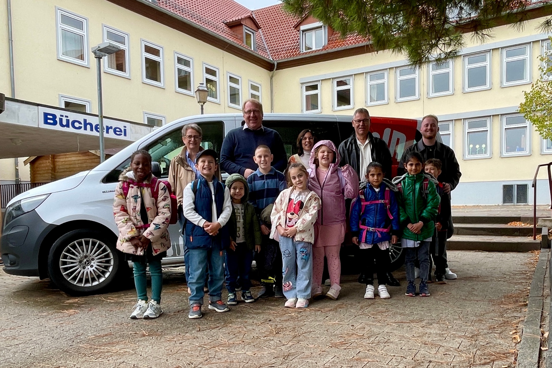Gruppenfoto mit Menschen vor Kleinbus