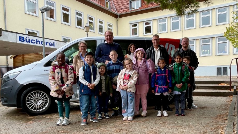 Gruppenfoto mit Menschen vor Kleinbus