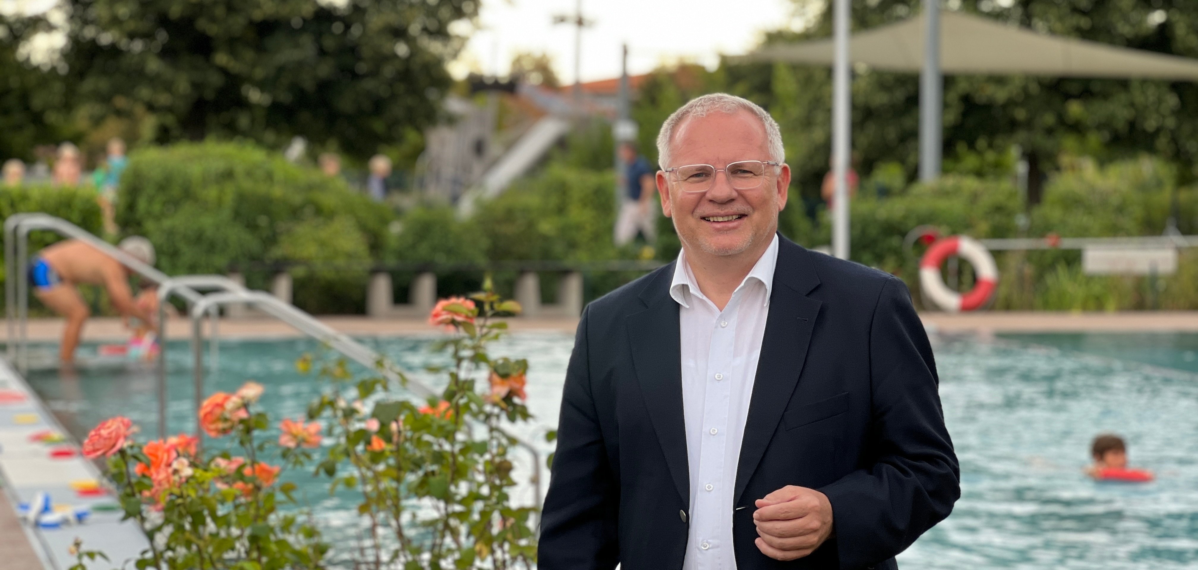 Landrat Ihlenfeld steht vor dem Schwimmbecken im Schwimmbad Wachenheim