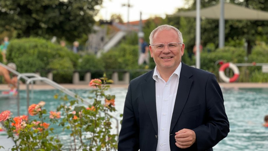 Landrat Ihlenfeld steht vor dem Schwimmbecken im Schwimmbad Wachenheim