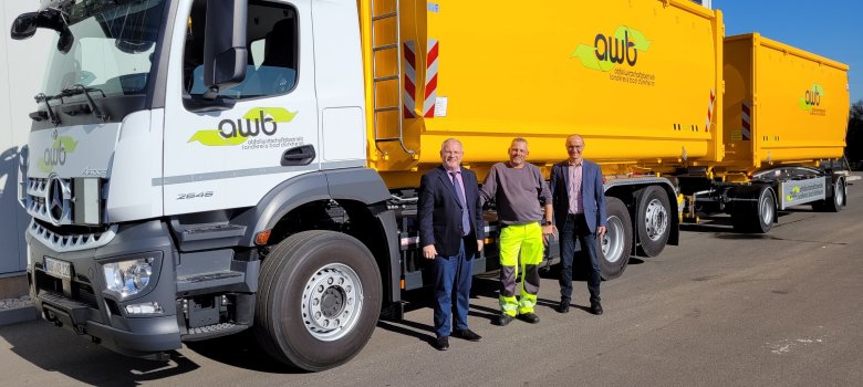 LKW mit gelben Containern, davor stehen von links Landrat Hans-Ulrich Ihlenfeld, der für das Fahrzeug zuständige Fahrer Tomasz Sadowski und AWB-Werkleiter Klaus Pabst