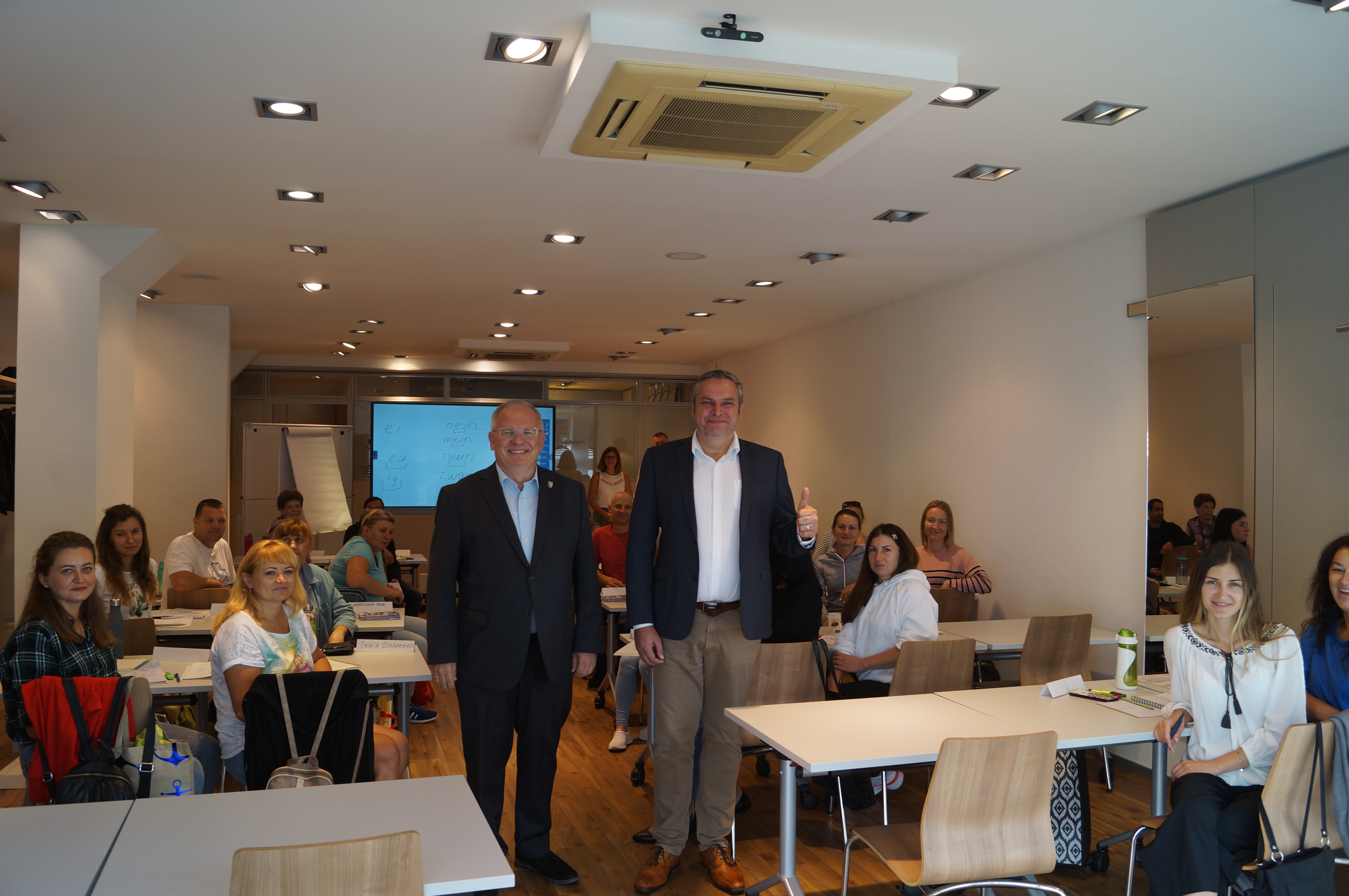 Landrat Ihlenfeld (li.) und KVHS-Leiter Dirk Michel im neuen Raum, im Hintergrund Schüler eines Integrationskurses