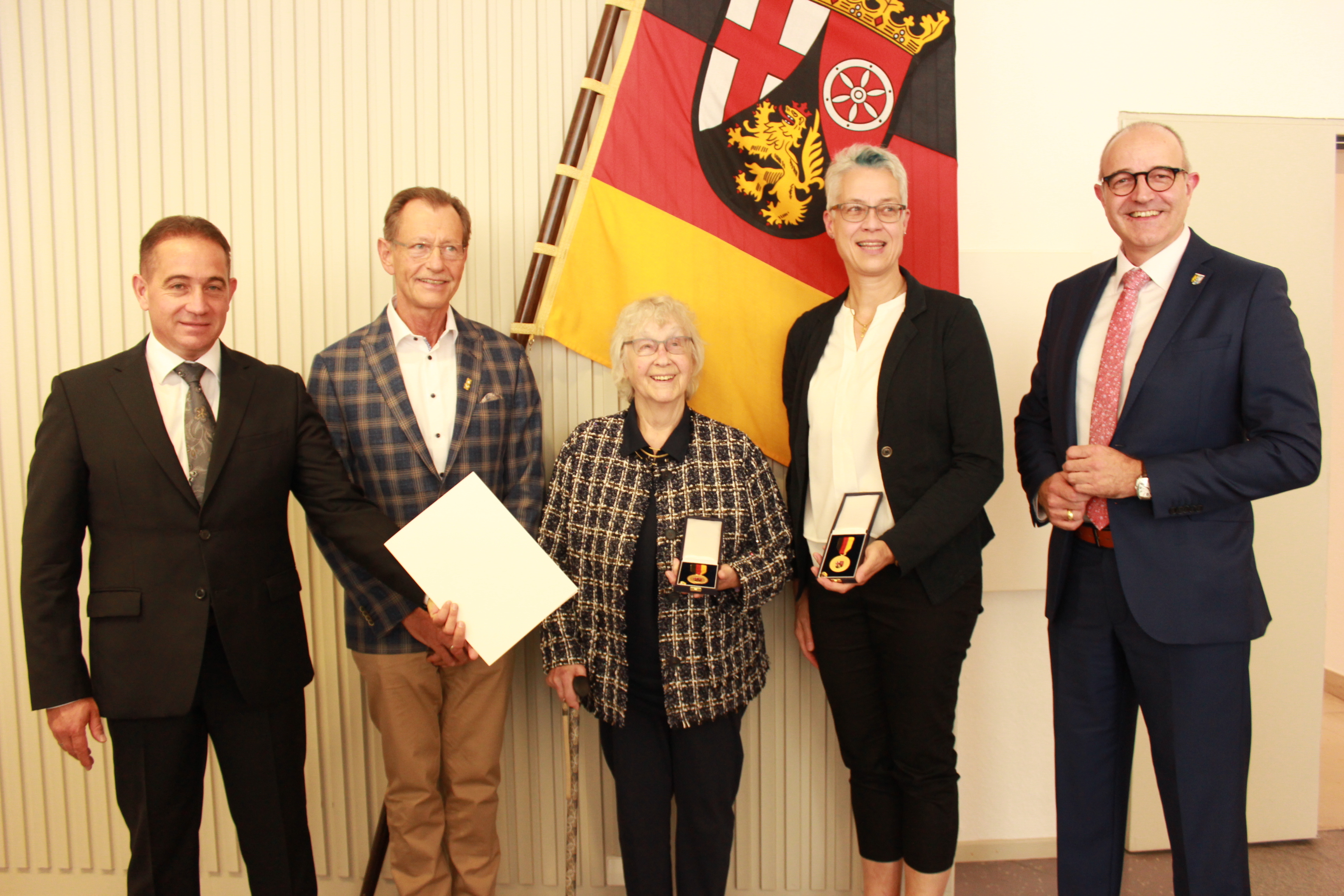 Eine Gruppe von fünf Personen, zwei davon mit Urkunde.