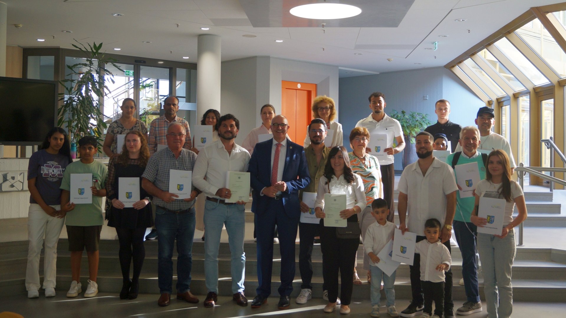 Gruppenfoto mit 26 eingebürgerten Personen, in der Mitte der Beigeordnete Sven Hoffmann.