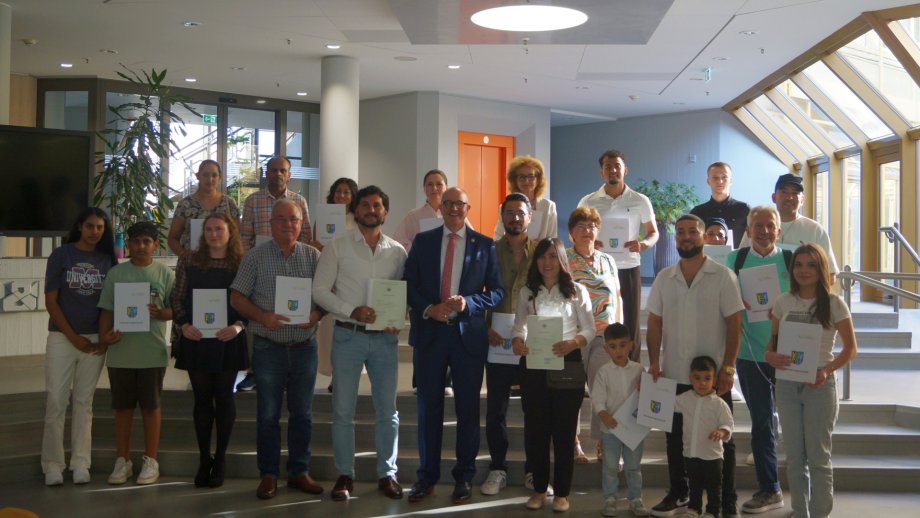 Gruppenfoto mit 26 eingebürgerten Personen, in der Mitte der Beigeordnete Sven Hoffmann.