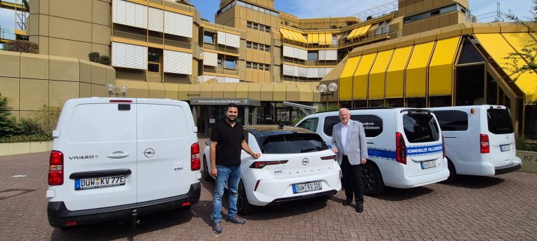 Zwei Männer stehen bei vier weißen Autos.