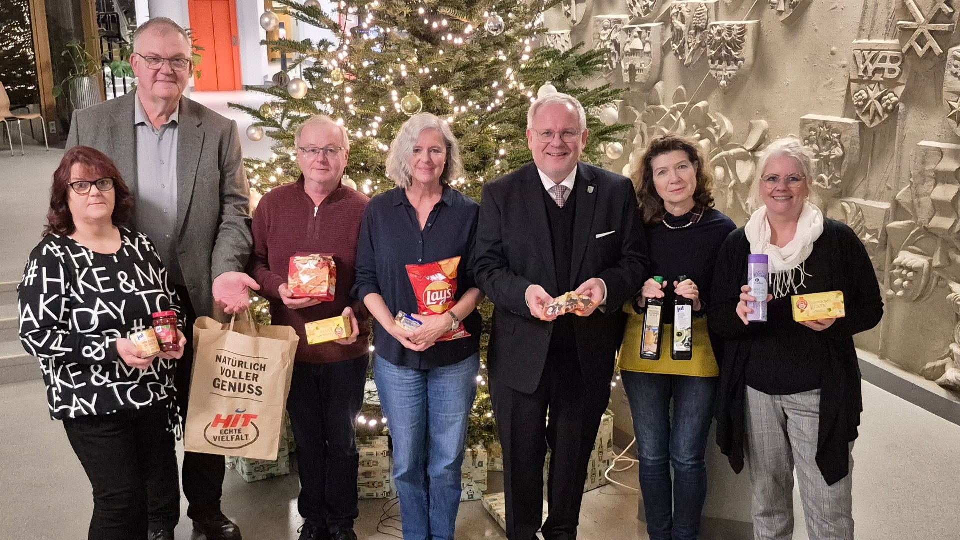 Menschengrupe vor Weihnachtsbaum.