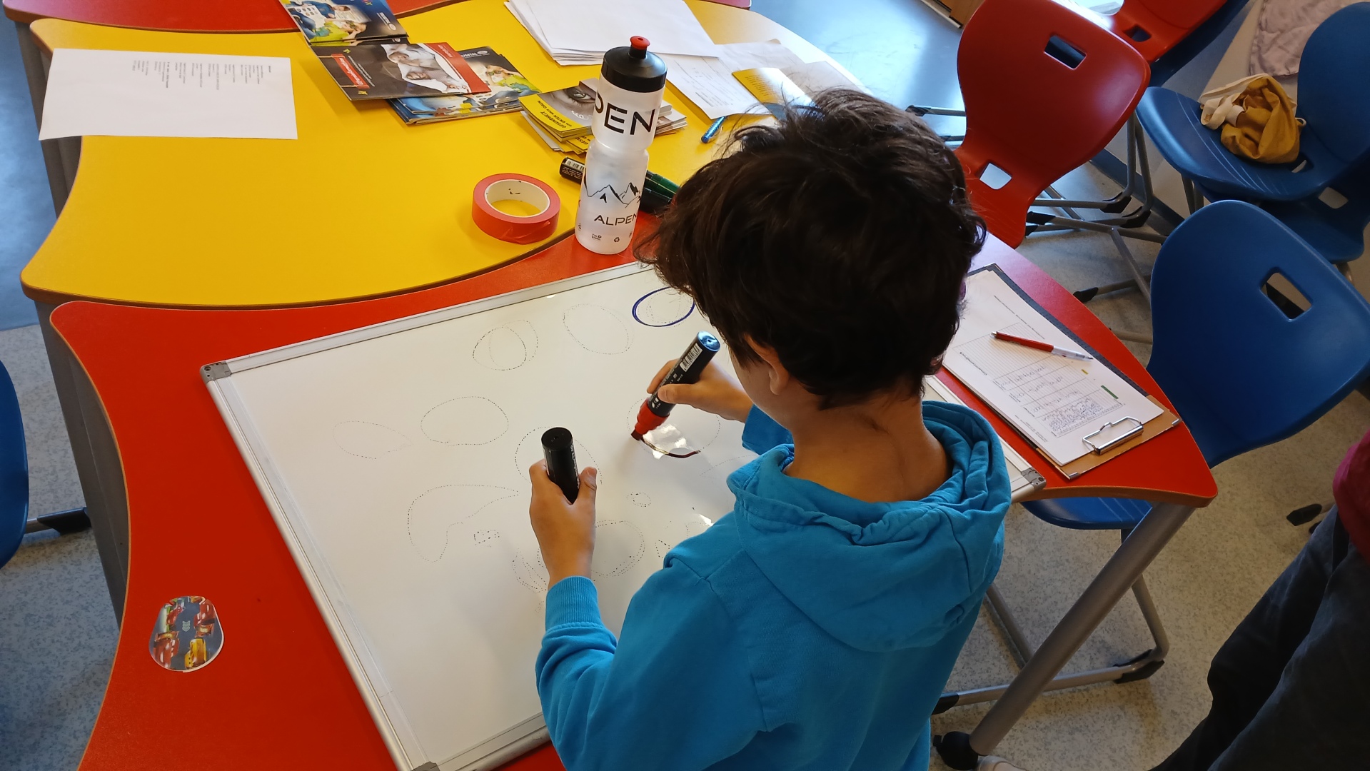 Ein Kind malt zwei Kreise auf eine Tafel