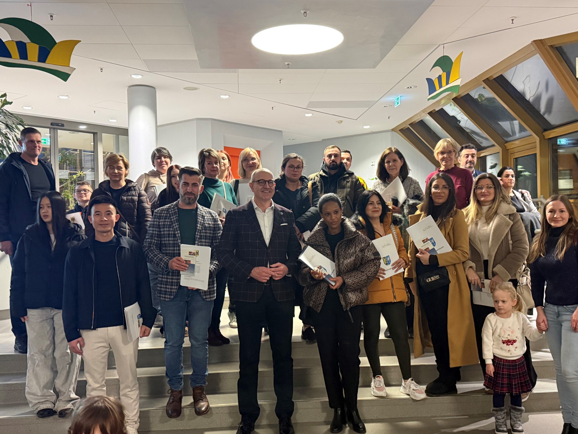 48 Personen stehen zusammen mit ihren Einbürgerungsurkunden; in der Mitte steht der Kreisbeigeordnete Sven Hoffmann.