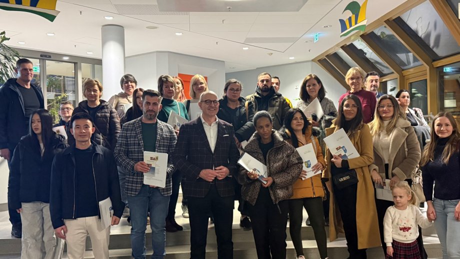 48 Personen stehen zusammen mit ihren Einbürgerungsurkunden; in der Mitte steht der Kreisbeigeordnete Sven Hoffmann.