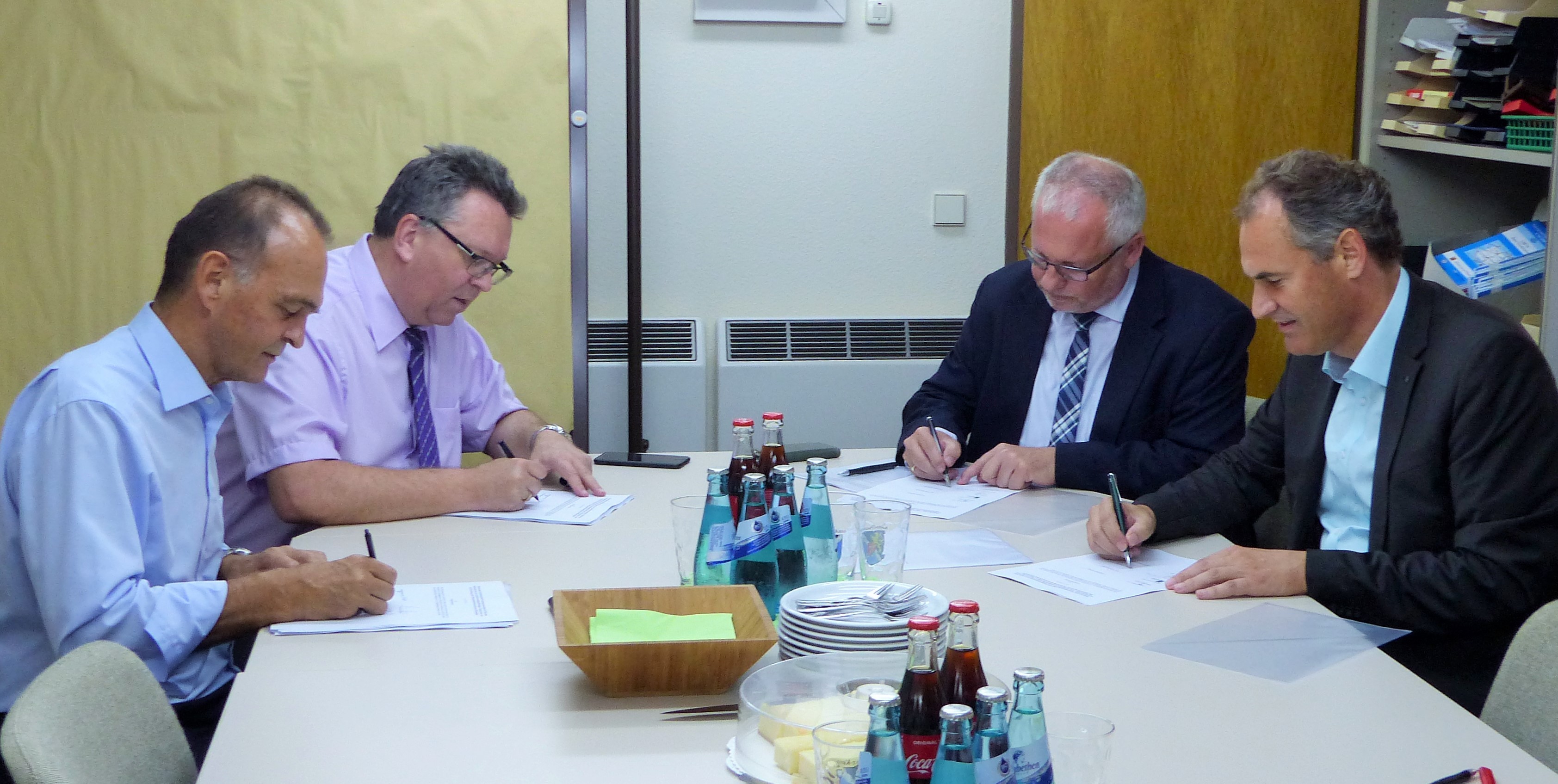 Landräte sitzen an Tisch und unterzeichnen Vertrag