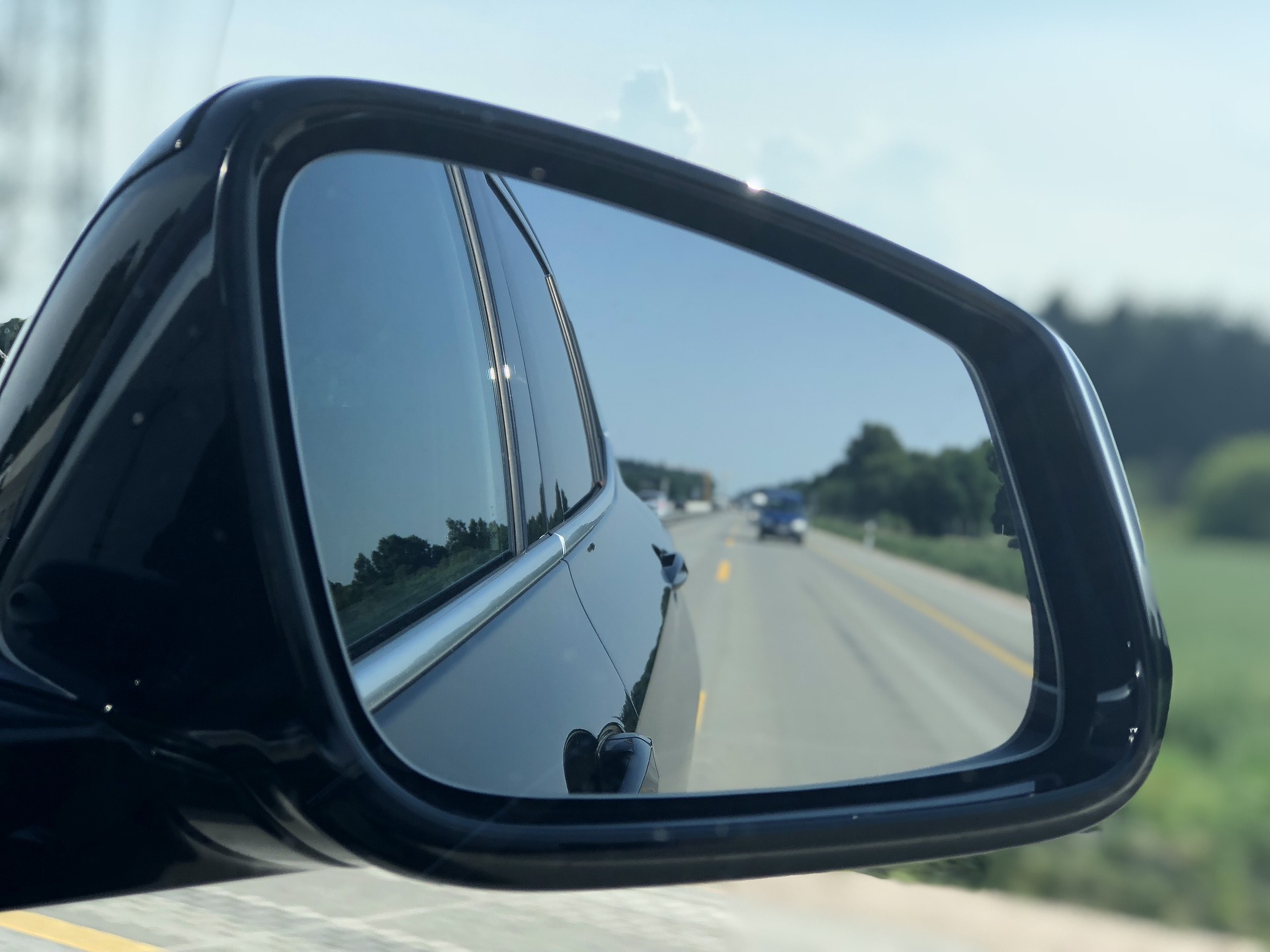 Rückspiegel eines Autos mit Blick auf Straße und Auto