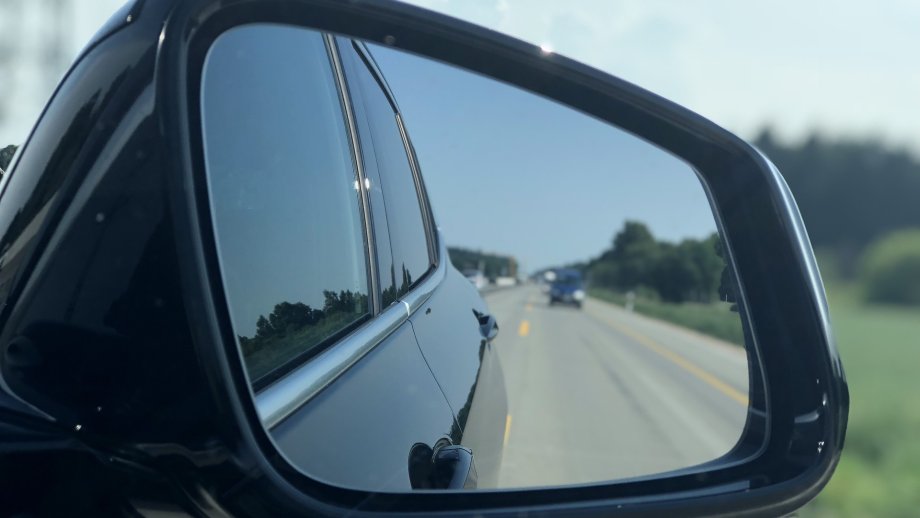 Rückspiegel eines Autos mit Blick auf Straße und Auto