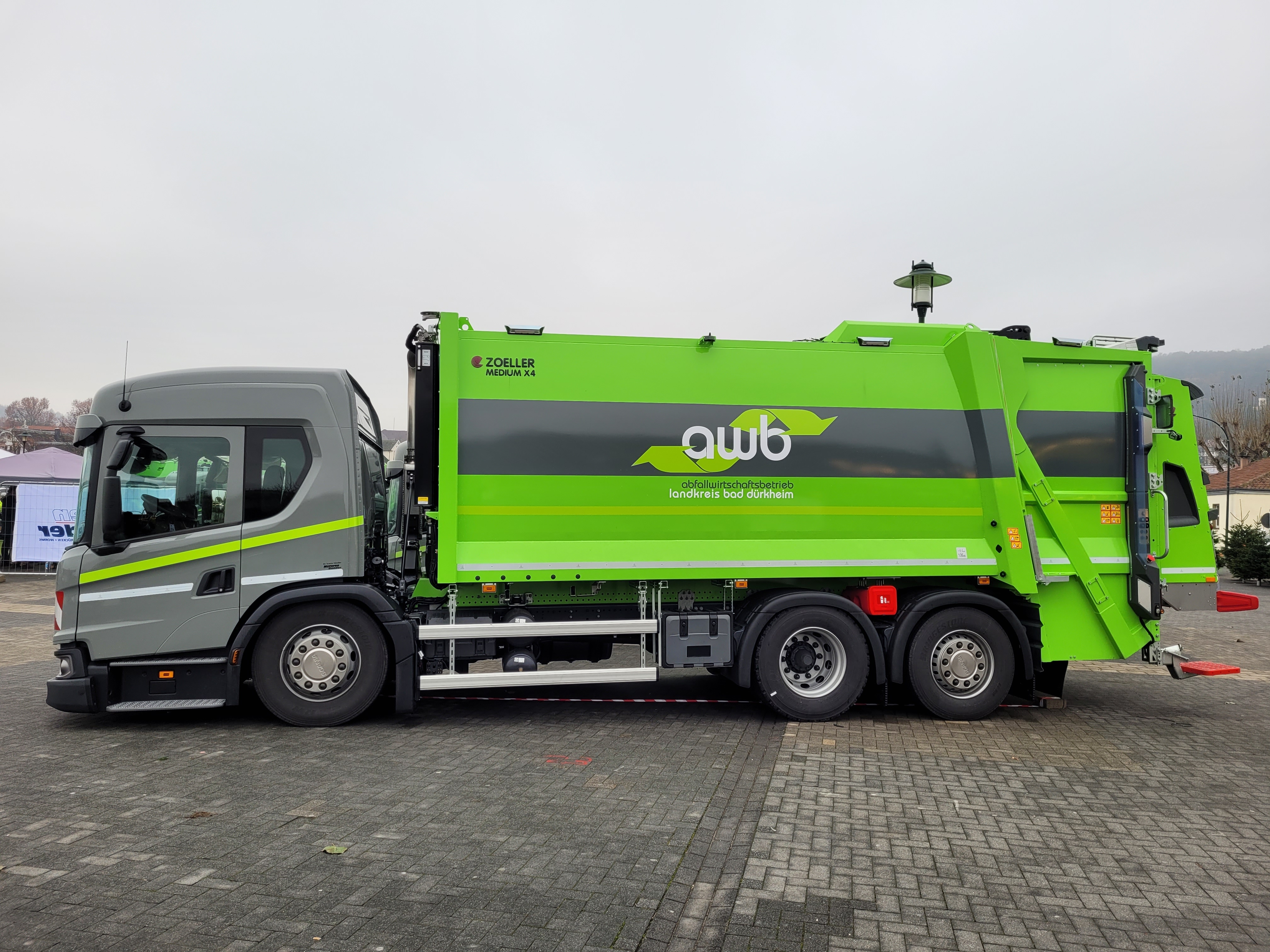 Ein Müllauto, das hellgrau und hellgrün lackiert ist m it dem Schriftzug "AWB". 