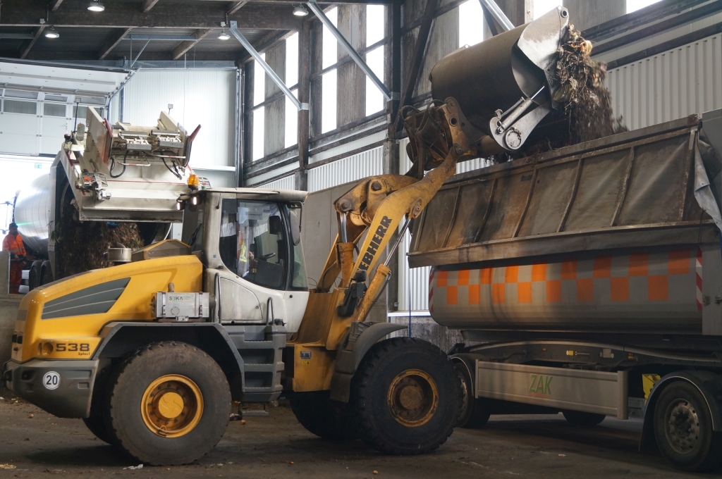 Lader bringt Abfall auf Fahrzeug