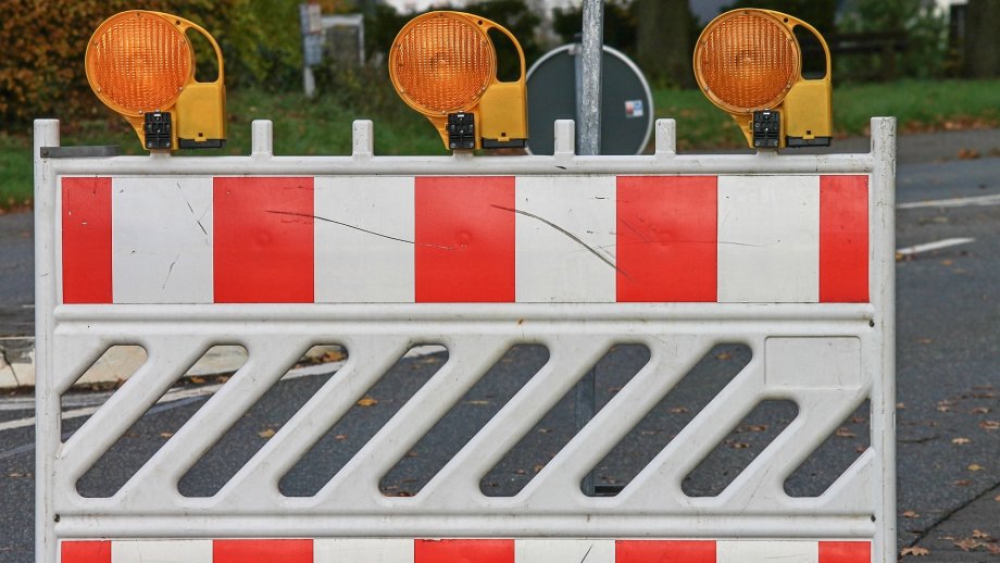 Rot-Weiße Straßenabsperrung mit gelben Warnleuchten. 