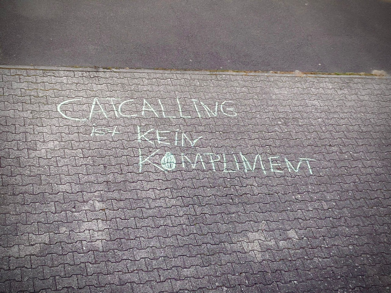 Auf eine mit Steinen gepflasterte Fläche ist "Catcalling ist kein Kompliment" geschrieben. 