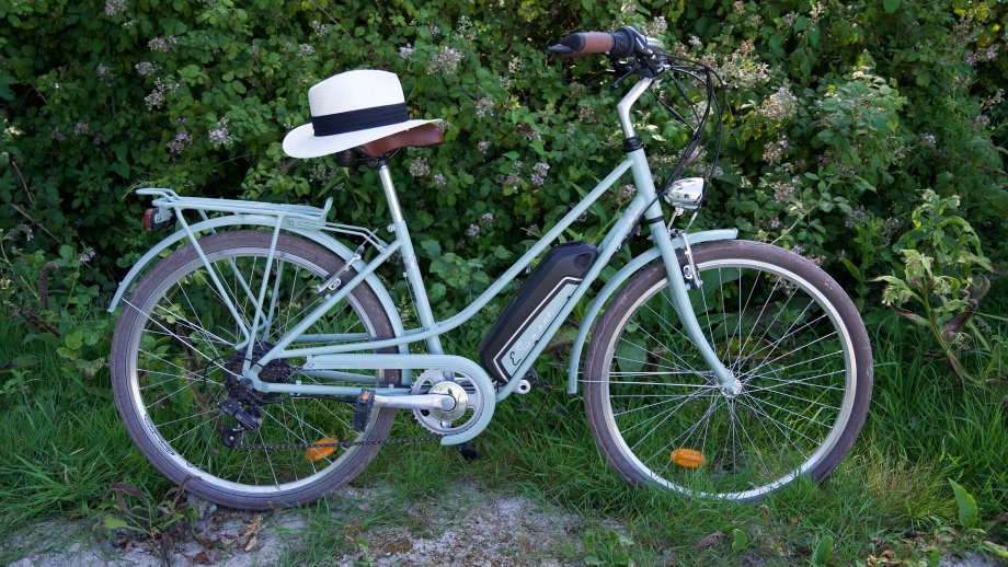 Hellgrünes E-Bike. Auf dem Sattel liegt ein weißer Hut.