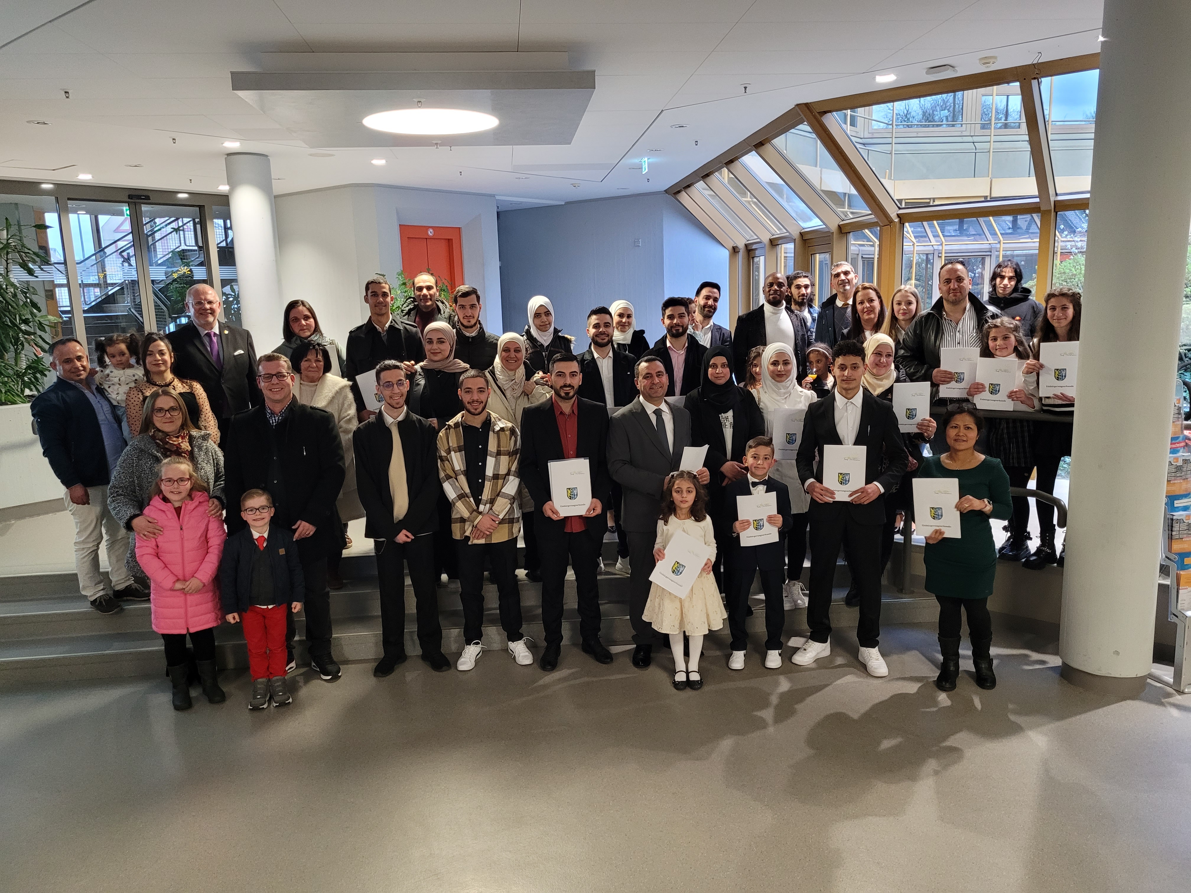 Eine Gruppe Menschen mit Einbürgerungsurkunden in der Hand.