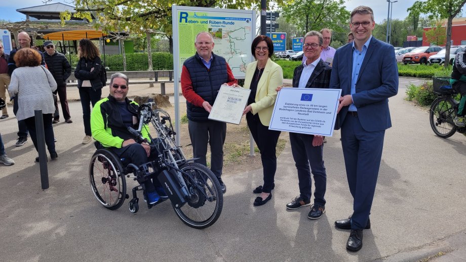 Ein Gruppenfoto mit einer Urkunde und einem Schild.