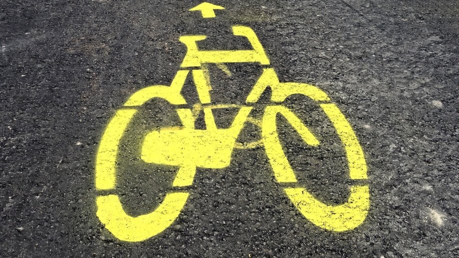 Ein gelbes Fahrrad ist auf Asphalt gesprüht.