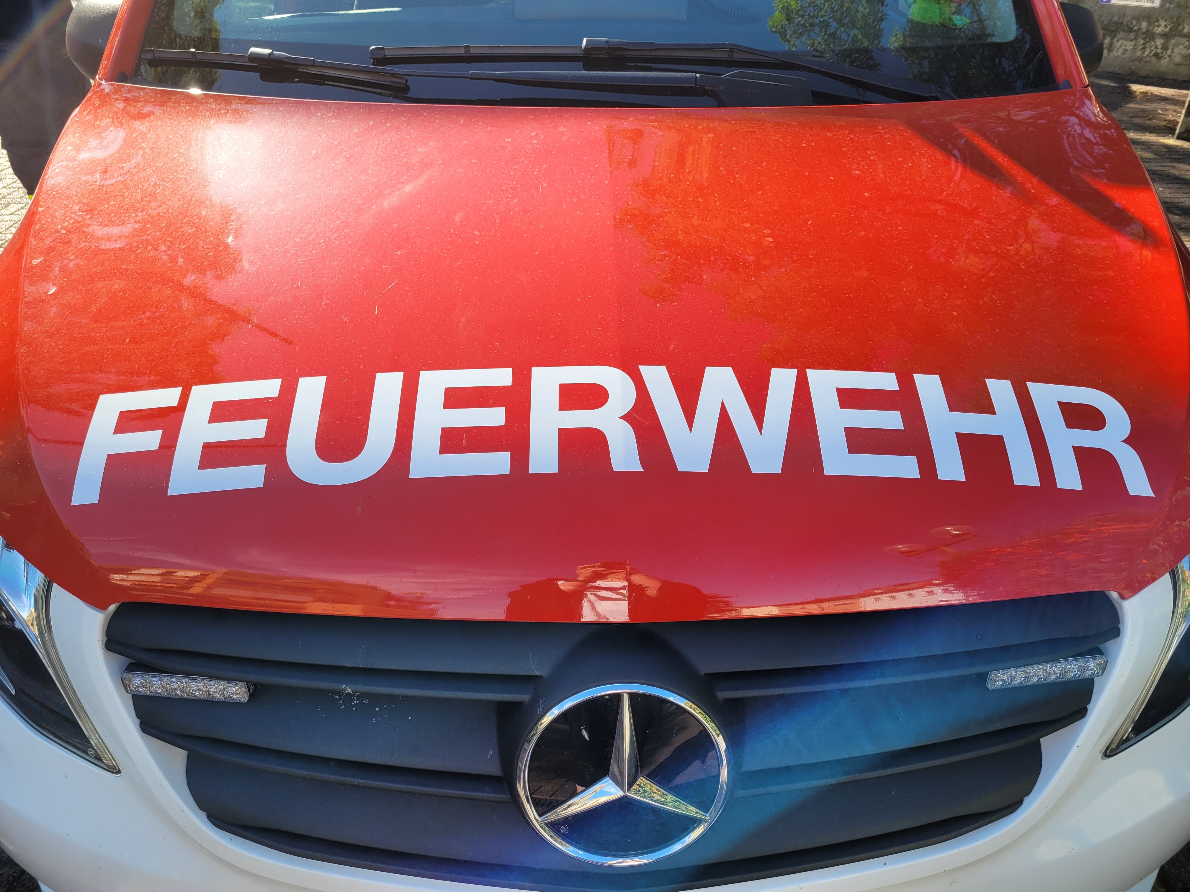 Der Schriftzug "Feuerwehr" auf der Kühlerhaube eines knallroten Feuerwehrautos. 