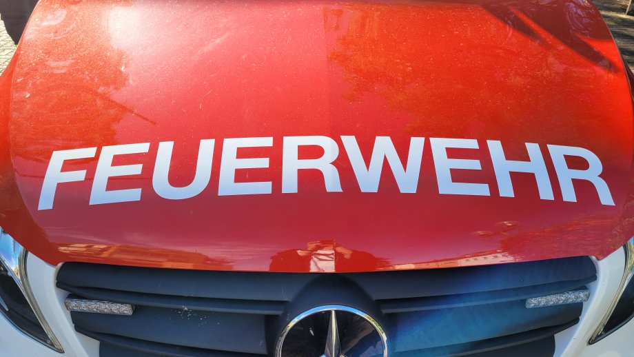 Der Schriftzug "Feuerwehr" auf der Kühlerhaube eines knallroten Feuerwehrautos. 