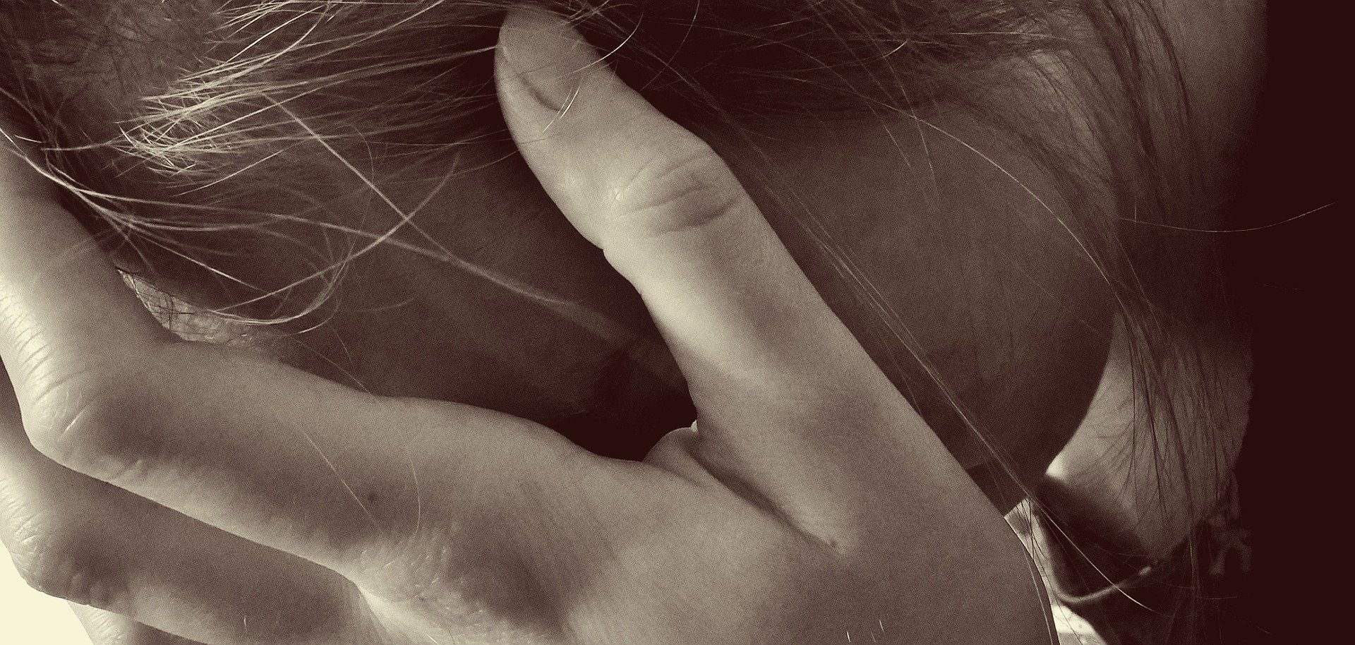 Großaufnahme einer Hand, die sich eine Frau vors Gesicht hält.