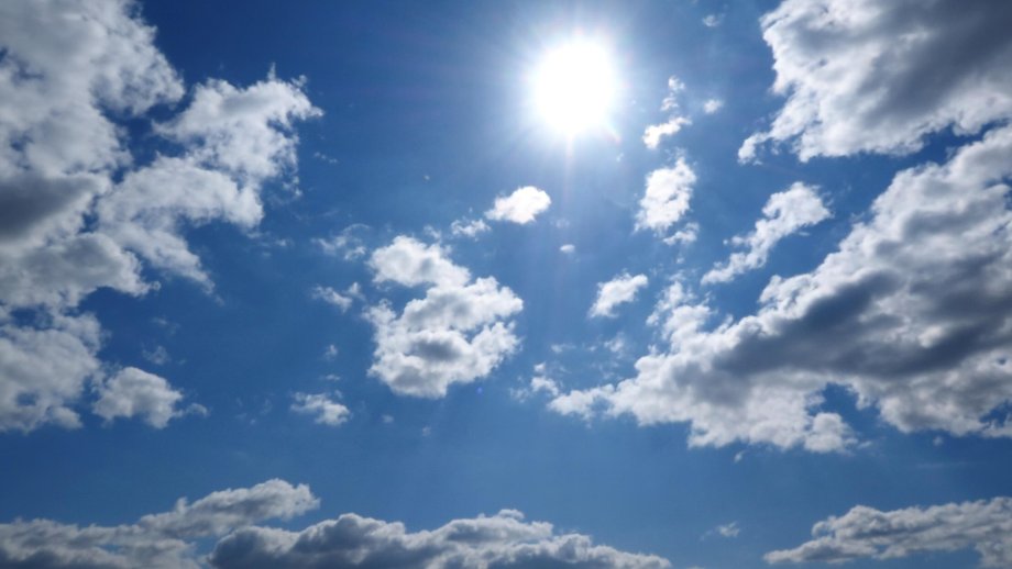 Sonne an blauem Himmel mit einigen Wolken