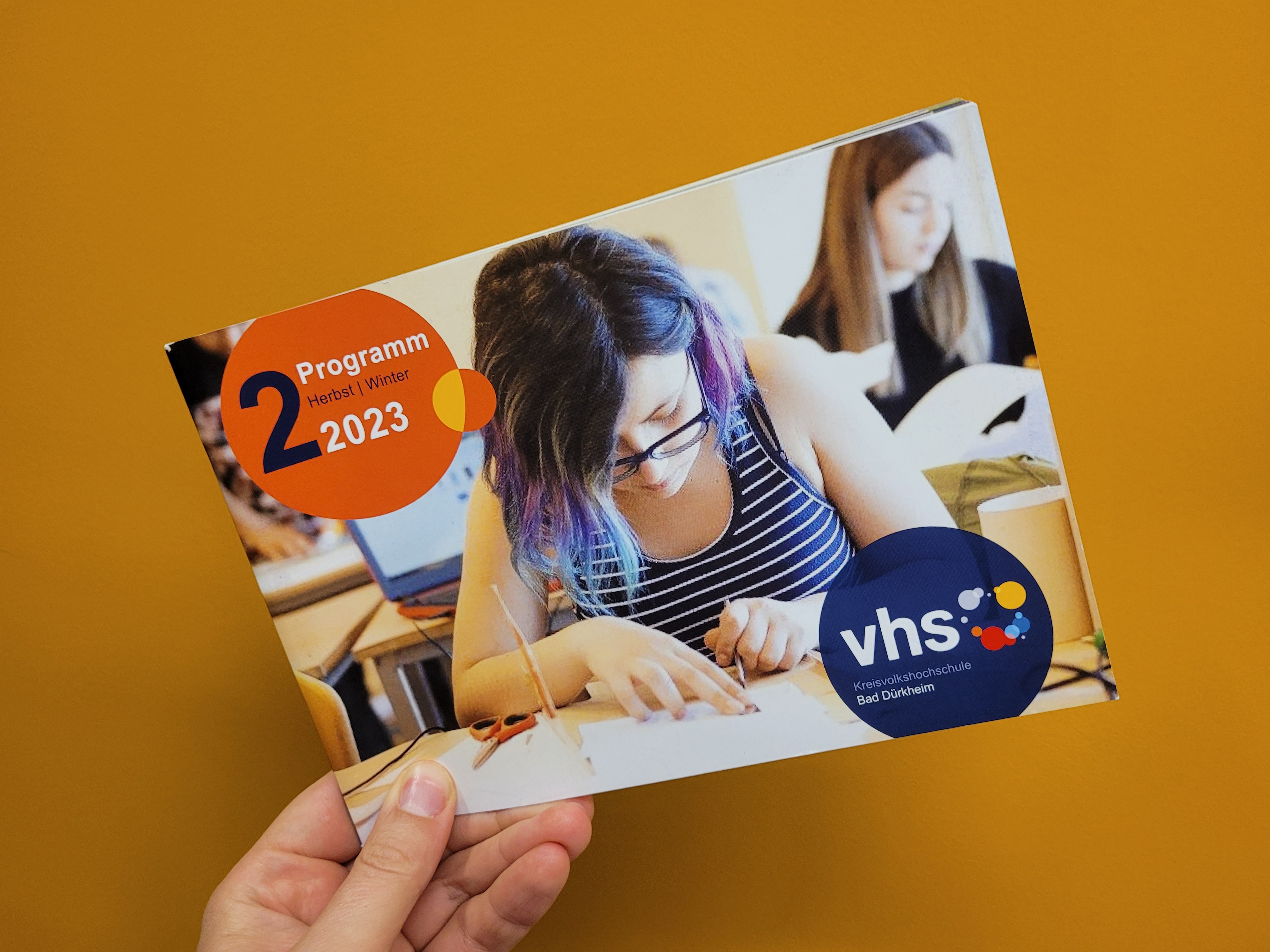 Das Programmheft der Kreisvolkshochschule vor einer gelben Wand. 