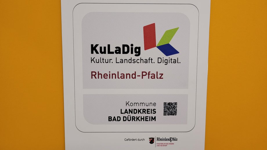 Die Kuladig-Plakette vor gelbem Hintergrund. 