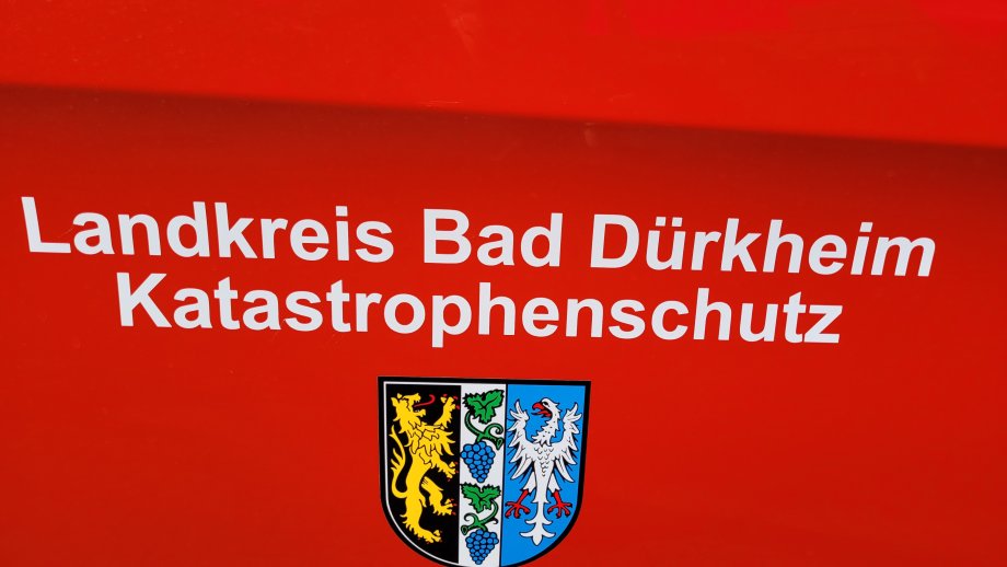Weißer Schriftzug "Landkreis Bad Dürkheim Katastrophenschutz" über dem Wappen des Landkreises, beides auf feuerwehrrotem Hintergrund. 