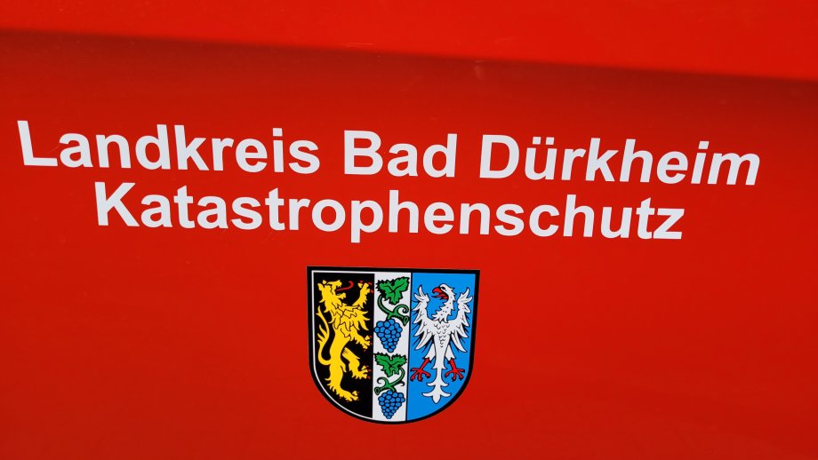 Weißer Schriftzug "Landkreis Bad Dürkheim Katastrophenschutz" über dem Wappen des Landkreises, beides auf feuerwehrrotem Hintergrund. 