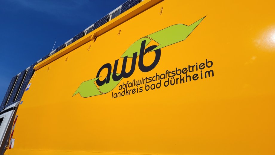 Ein gelber Container mit dem AWB-Logo auf einem LKW. 