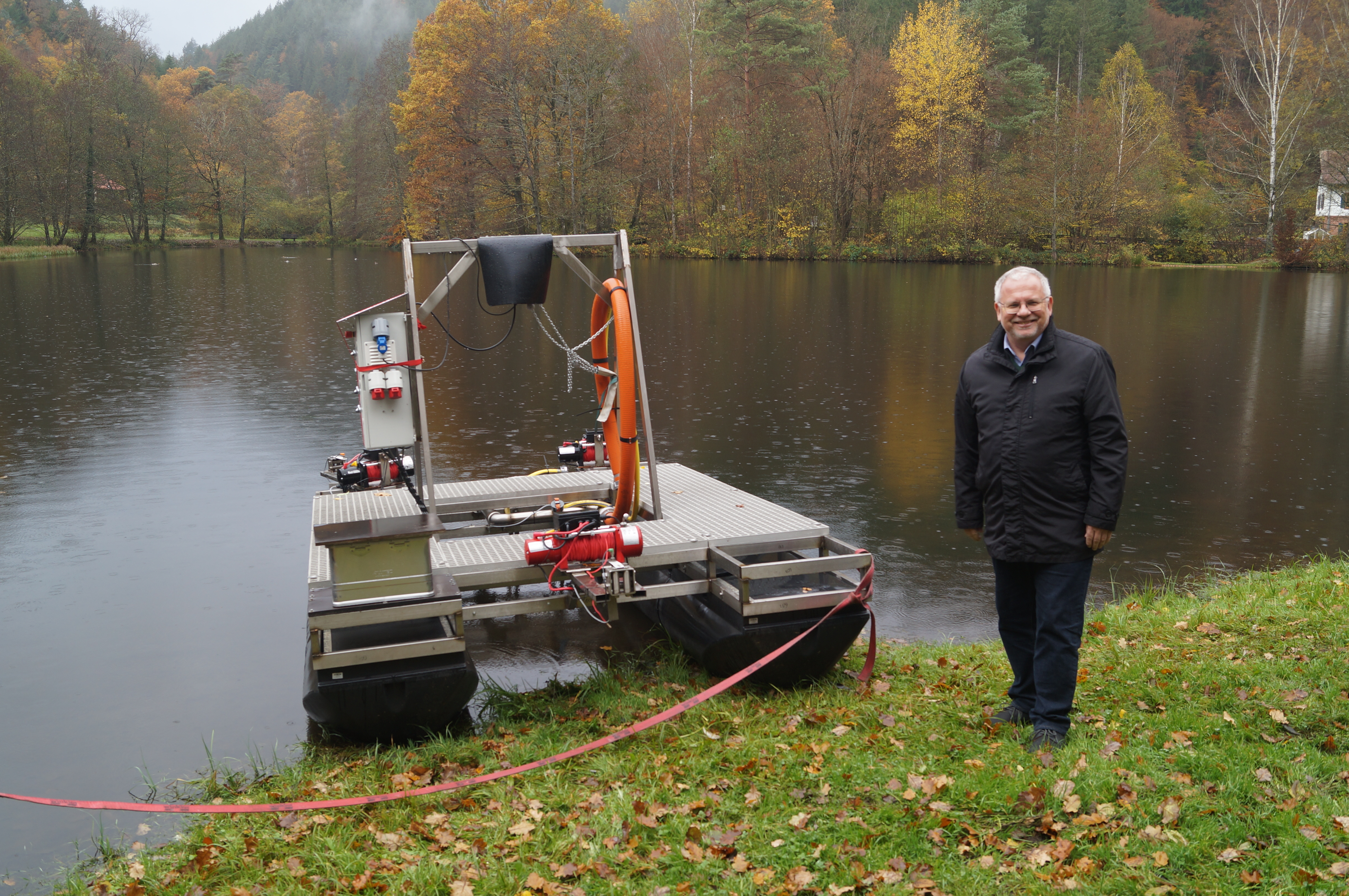 Ein Mann steht neben einem Gerät, dass nach einer Mischung aus Floß und Schlauchboot aussieht. 