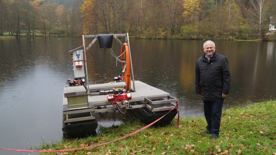 Ein Mann steht neben einem Gerät, dass nach einer Mischung aus Floß und Schlauchboot aussieht. 