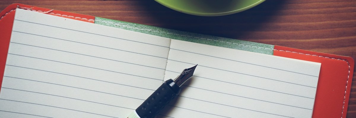Grüne Tasse und Notizbuch mit Füllfederhalter