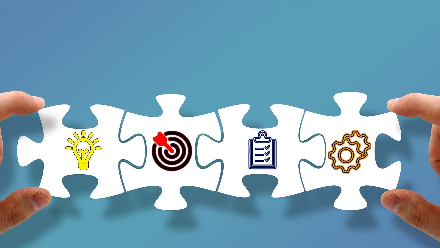 Zwei Hände halten vier ineinander gesteckte Puzzleteile mit Symbolen.