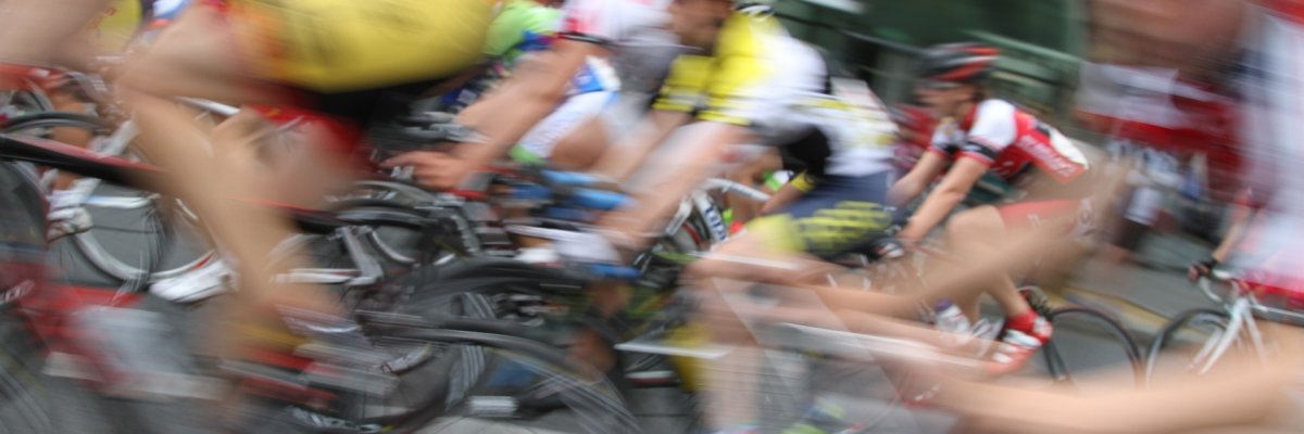 Eine Gruppe Radsportler fährt bei einem Rennen schnell vorbei, Bild leicht verschwommen.