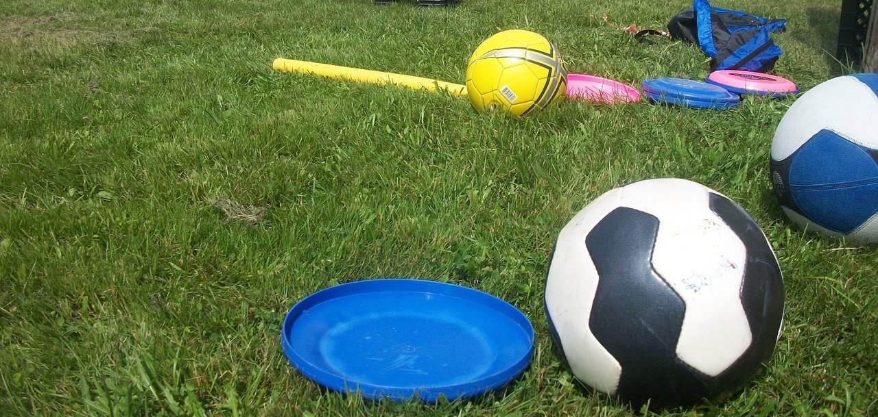 Auf einem Rasen liegen Bälle und andere Spielsachen. 