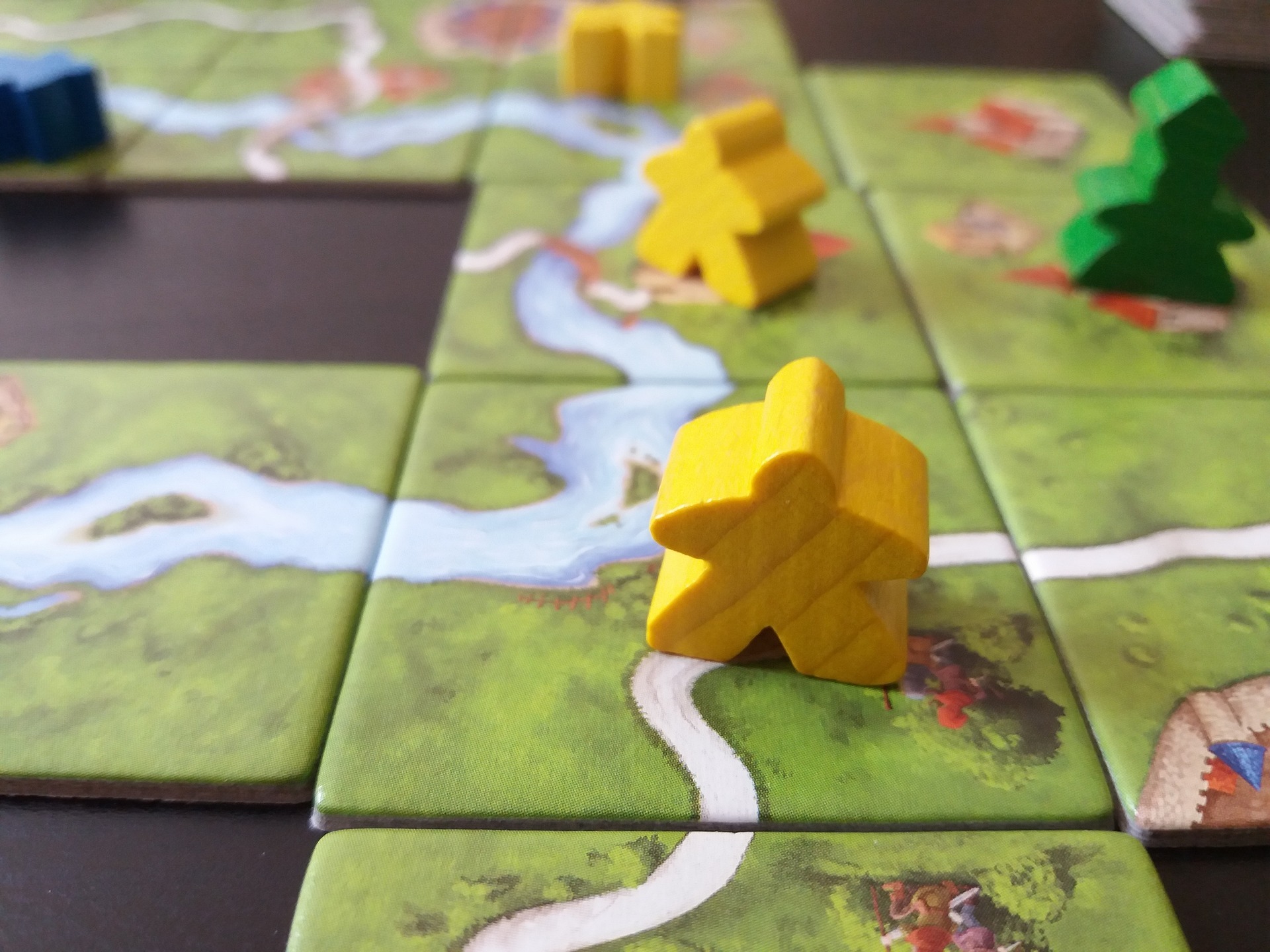 Spielfiguren auf Landschaftsplättchen aus dem Spiel "Carcassonne",