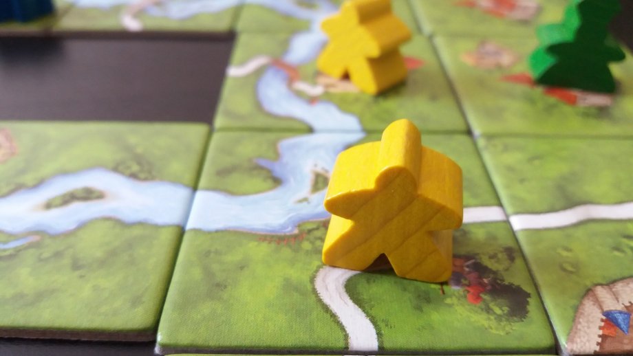 Spielfiguren auf Landschaftsplättchen aus dem Spiel "Carcassonne",