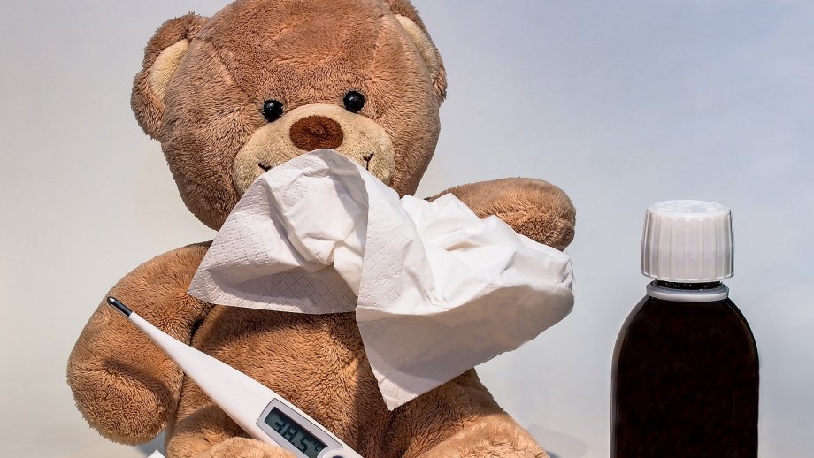 Teddybär mit Papiertaschentuch, Fieberthermometer und Medizin. 