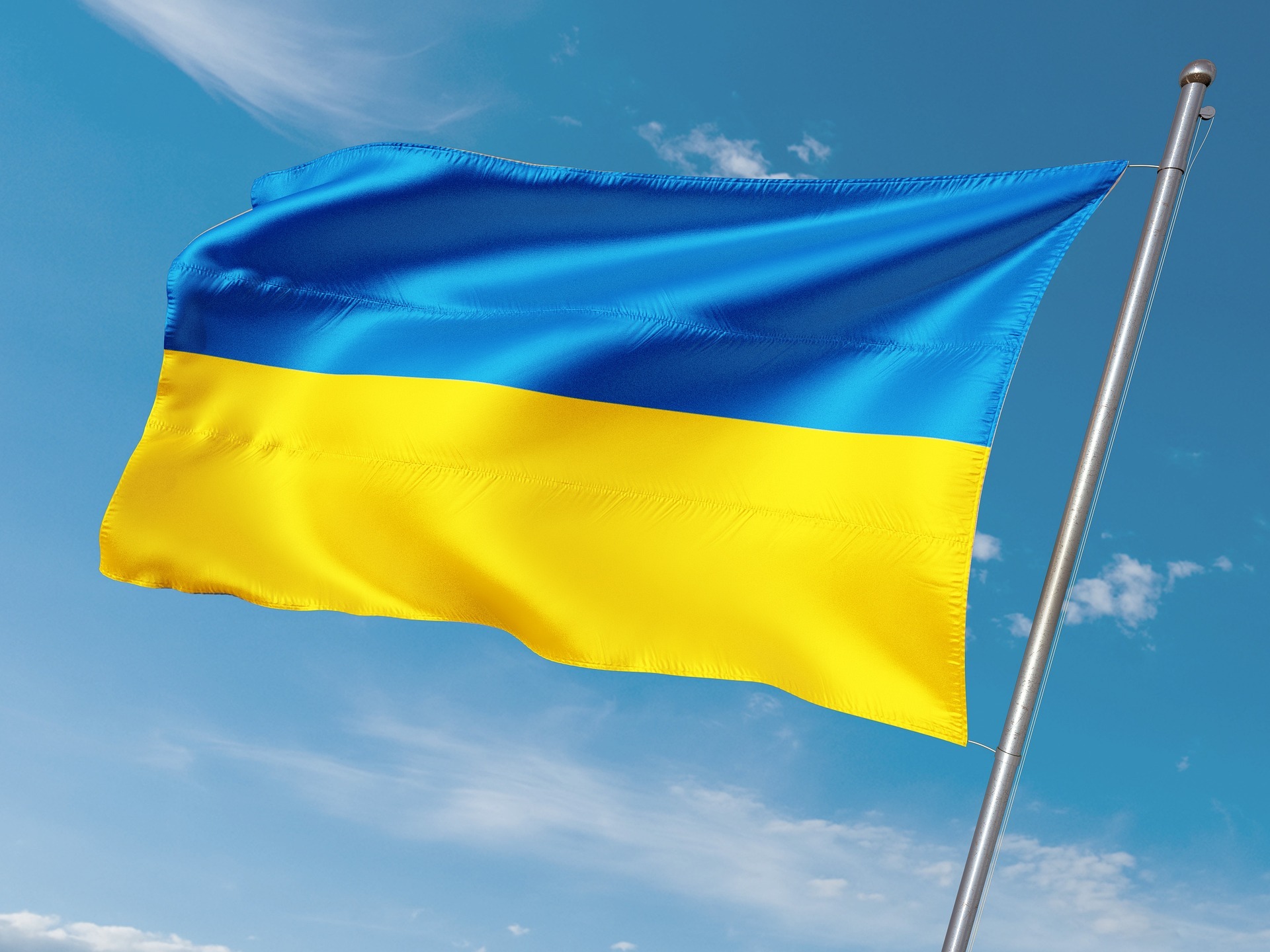 Eine ukrainische Fahne weht vor blauem Himmel.