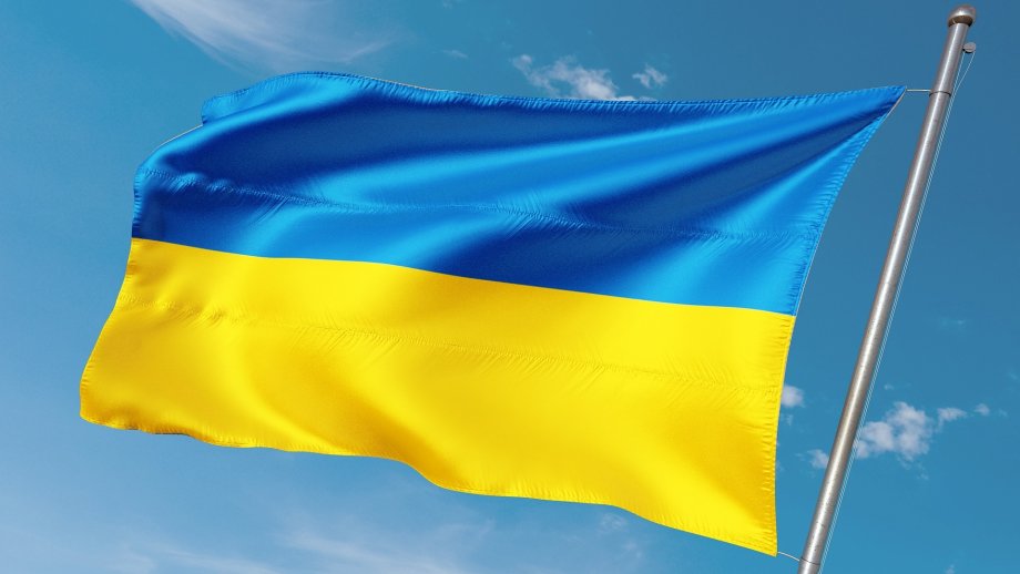 Eine ukrainische Fahne weht vor blauem Himmel. 