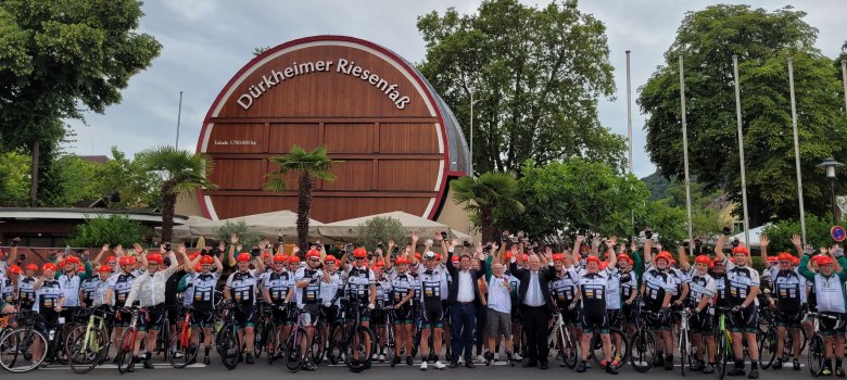 Eine lange Reihe gleich gekleideter Radfahrer der "Vor-Tour der Hoffnung" steht vor dem Riesenfass in Bad Dürkheim. 