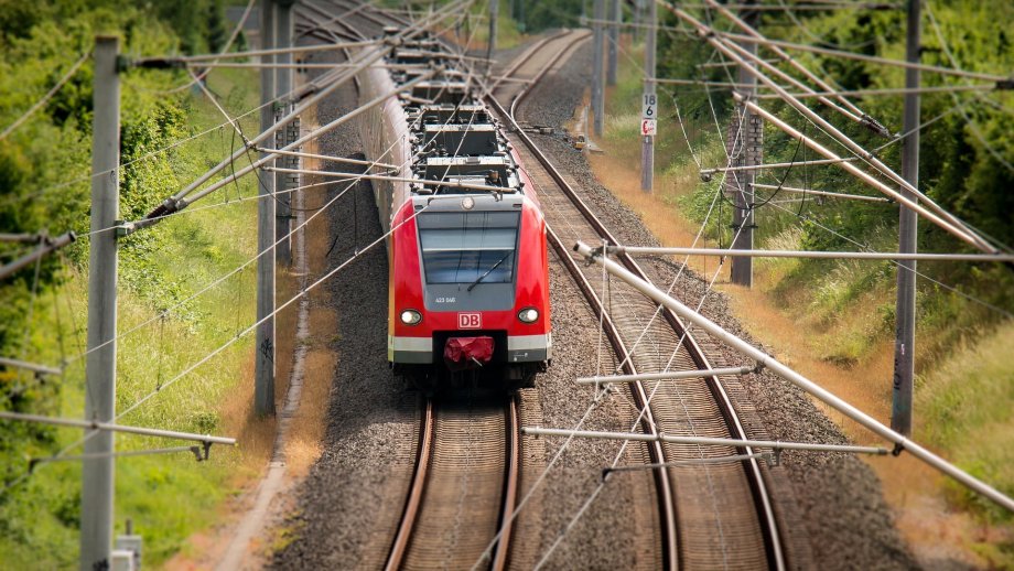 Roter Zug der DB fährt auf Schienen