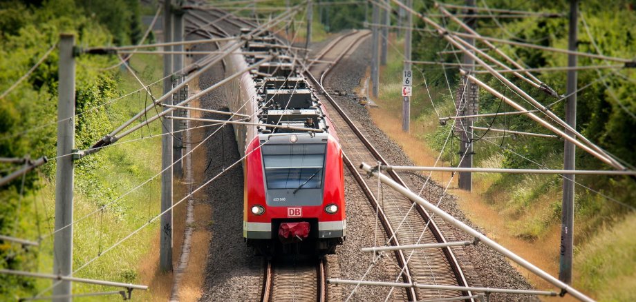 Roter Zug der DB fährt auf Schienen