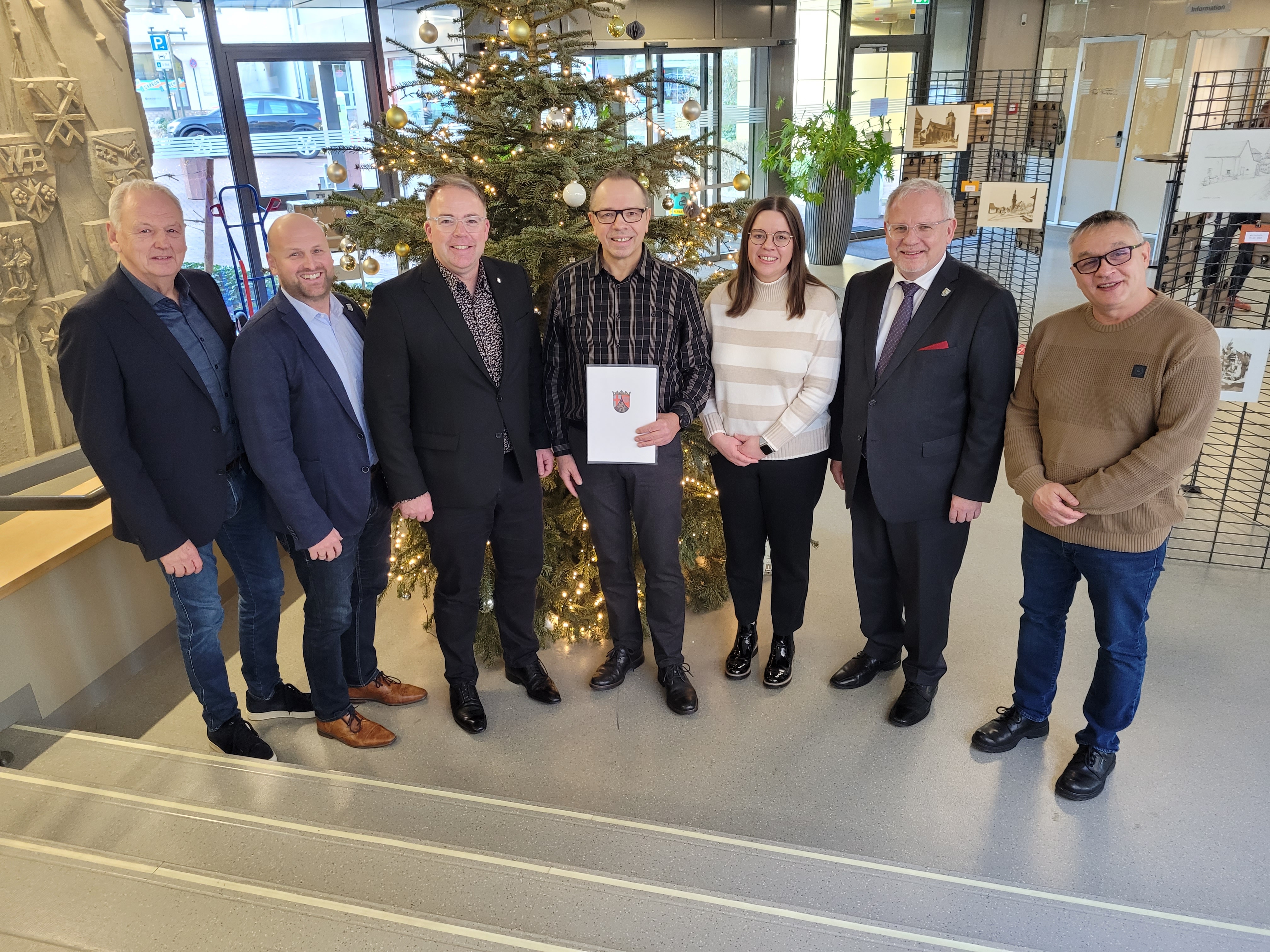 Eine Gruppe Menschen steht vor einem Weihnachtsbaum.